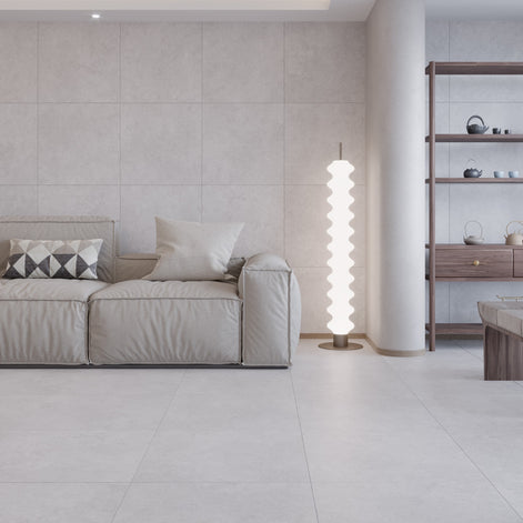 Modern living room with a beige sofa, floor lamp, and shelves with an off white floor and wall tile